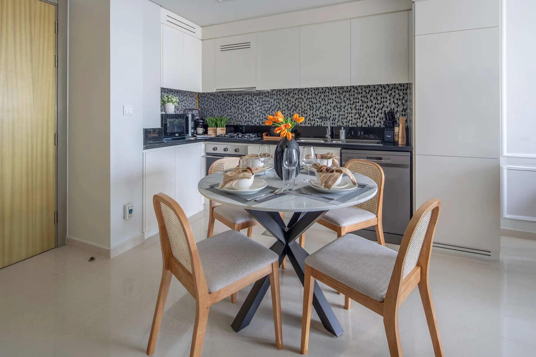 Un comedor con la mesa puesta y una cocina al fondo.