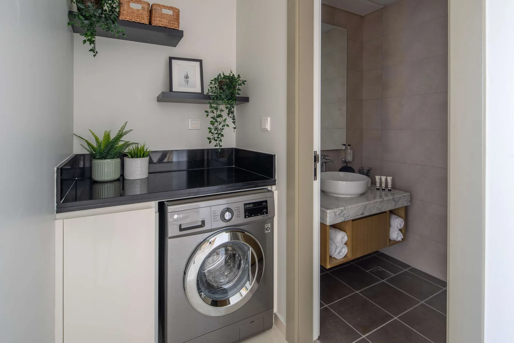 Una zona de lavandería con lavadora está junto a un lavabo de baño.