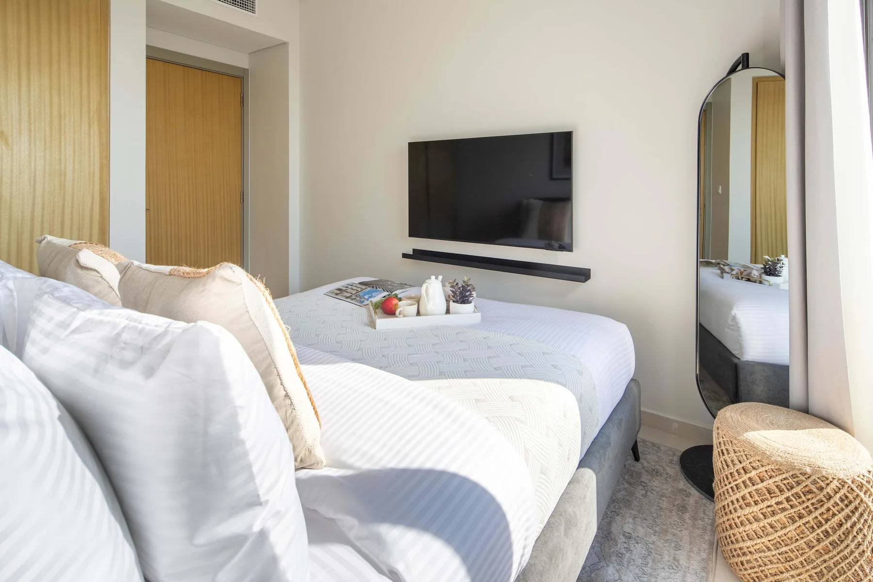 Un dormitorio con camas, un televisor en la pared y un espejo de cuerpo entero.