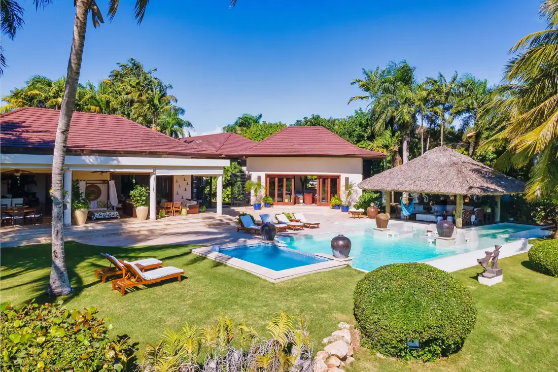 Un patio de estilo tropical con piscina, asientos para descansar y palmeras.