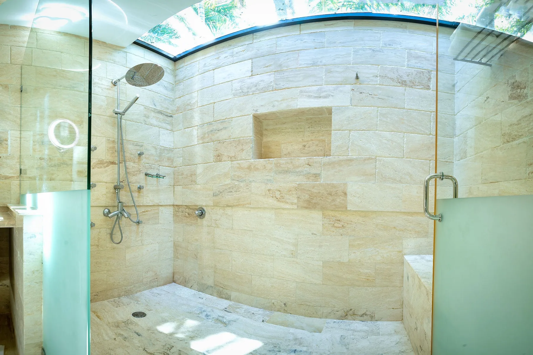 Una zona de ducha con azulejos, una ducha mural y un nicho en la pared.
