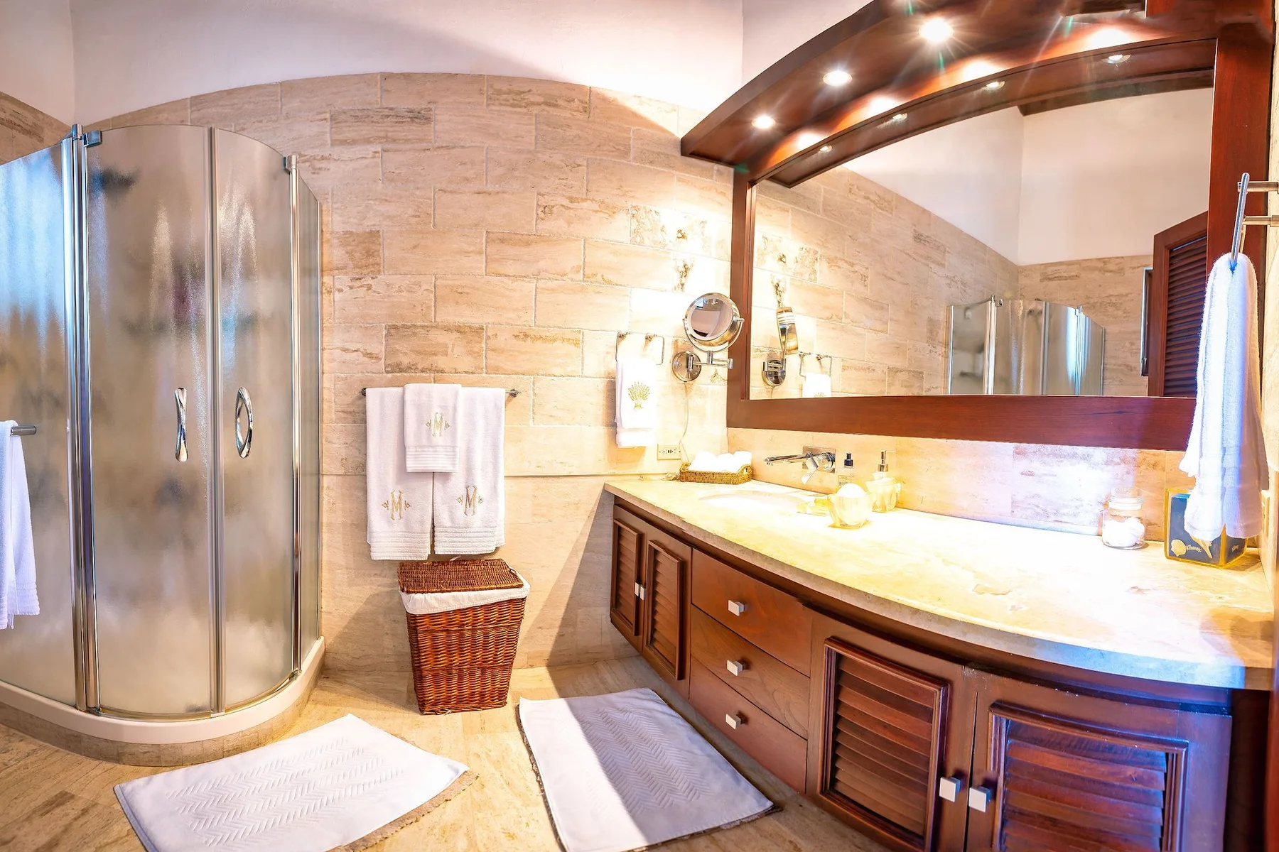 Un baño con una ducha de vidrio curva, un lavabo y un espejo grande.