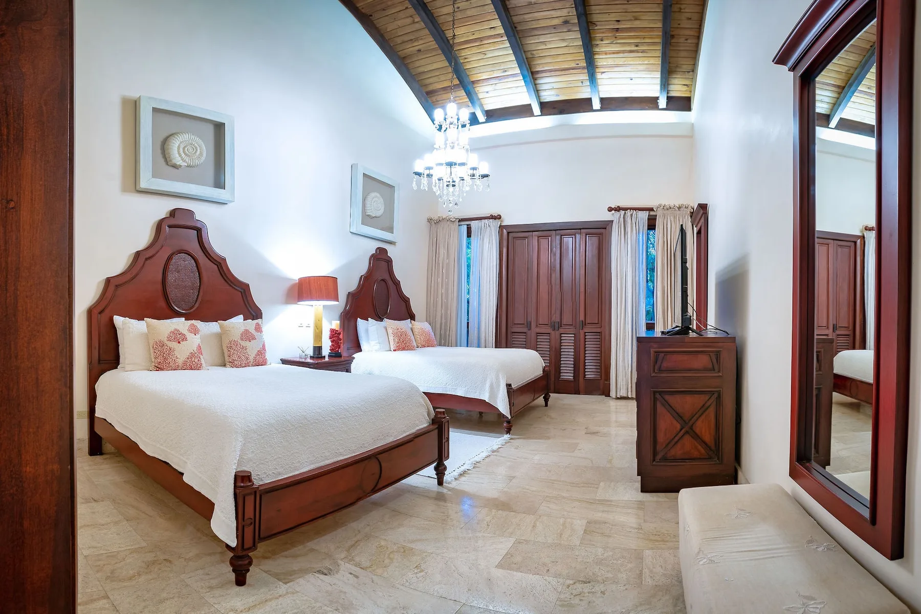 Dormitorio con dos camas, cabeceros de madera y un techo alto con vigas expuestas.