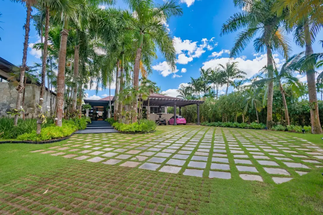 Un patio exterior ajardinado con una amplia zona pavimentada y palmeras.