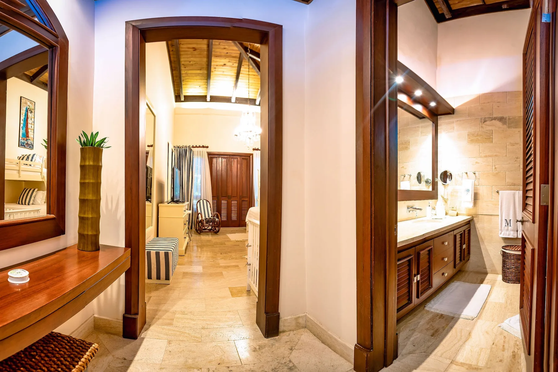 Un pasillo da a un dormitorio y un baño, con molduras de madera y suelos de baldosas.
