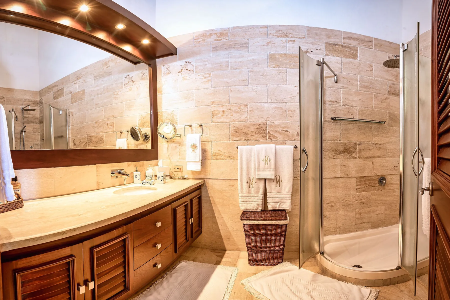 Un baño con tocador, espejo de pared y ducha con mampara de vidrio.