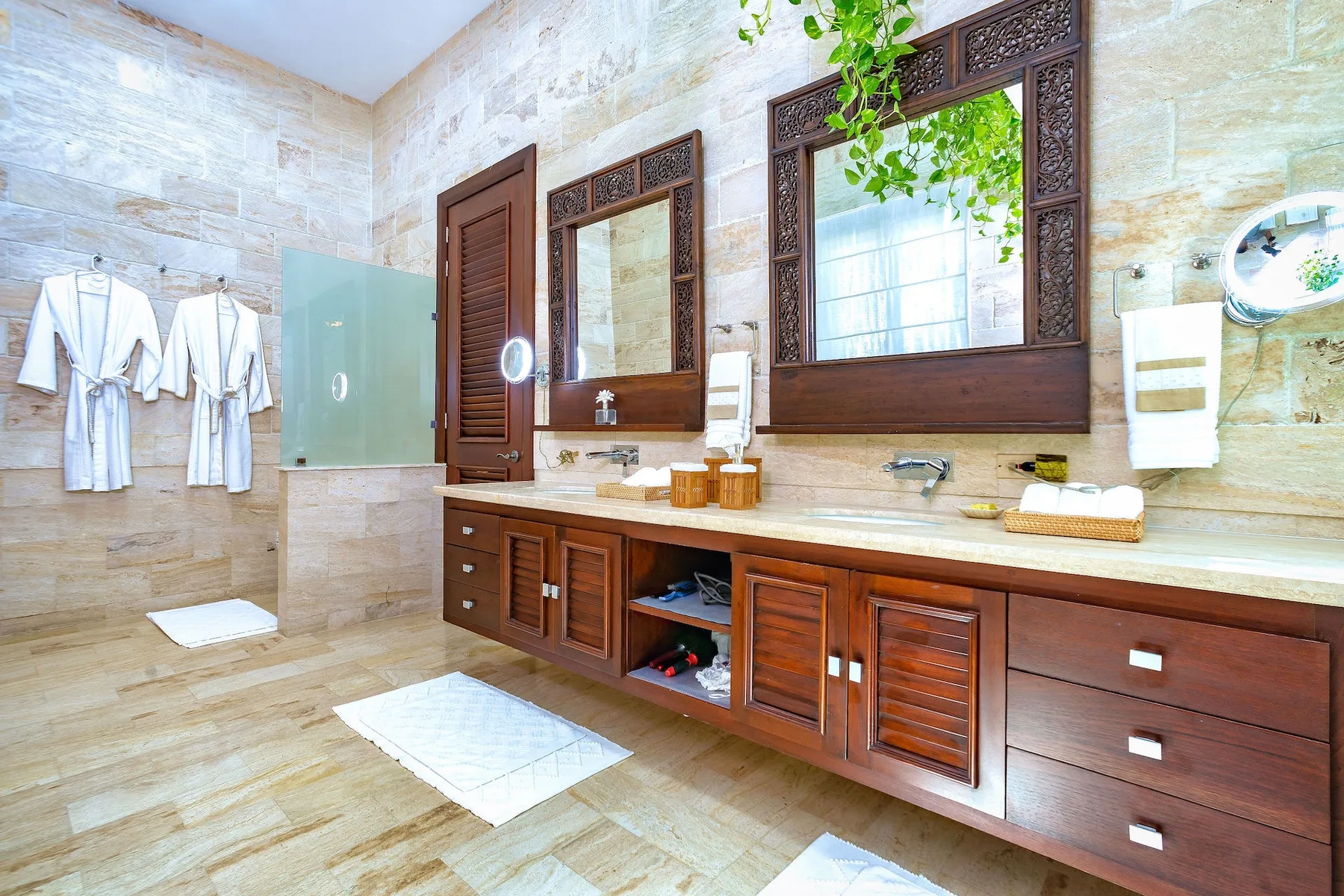 Un baño luminoso con un tocador largo, espejos y batas colgadas.