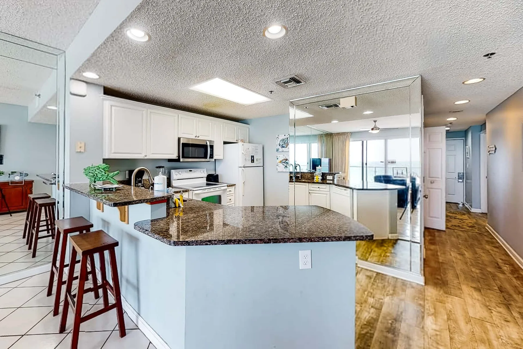 A bright kitchen with a large island and a row of bar stools.