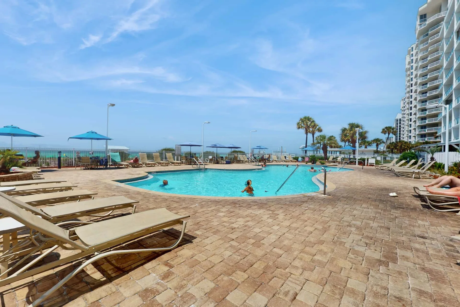 An outdoor swimming pool with lounge seating and a view of the ocean.