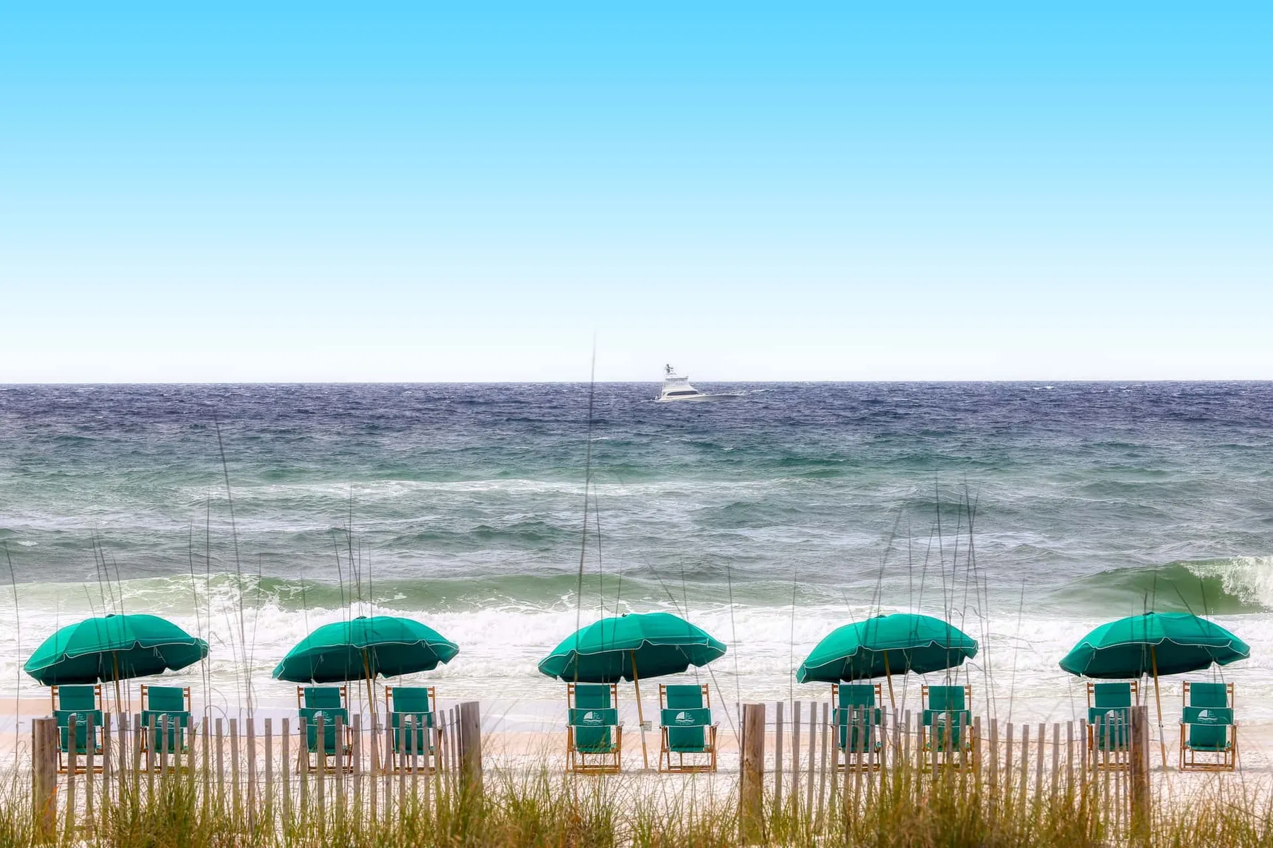 A beach scene with green umbrellas and ocean waves.