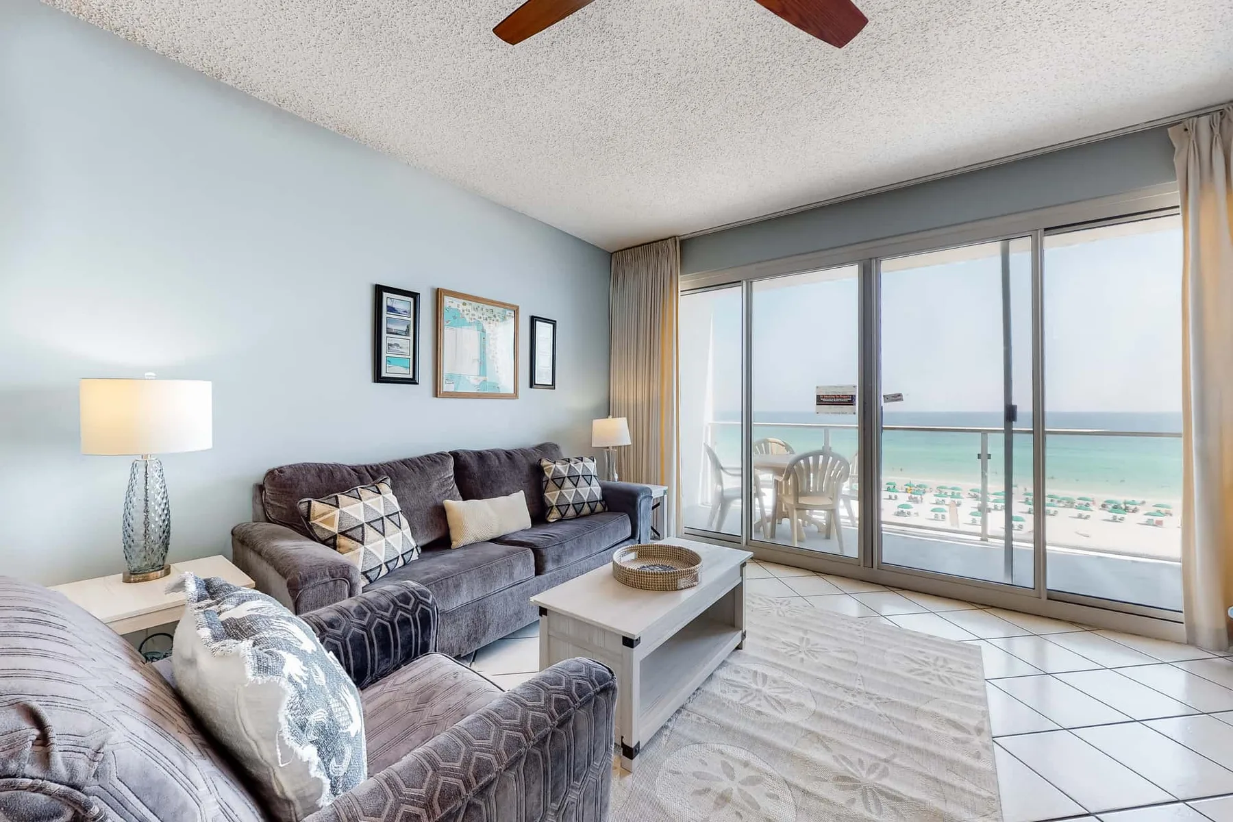 A living room with seating and a coffee table facing large windows overlooking the beach.
