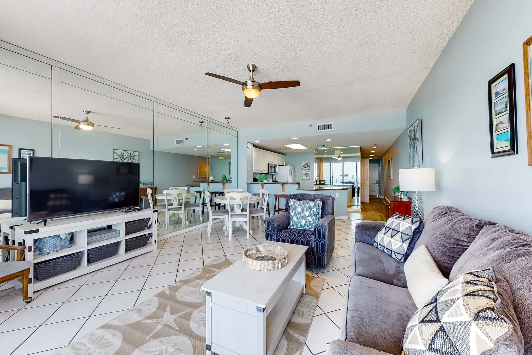 An open-plan living and dining area with a television, seating, and a kitchen beyond.