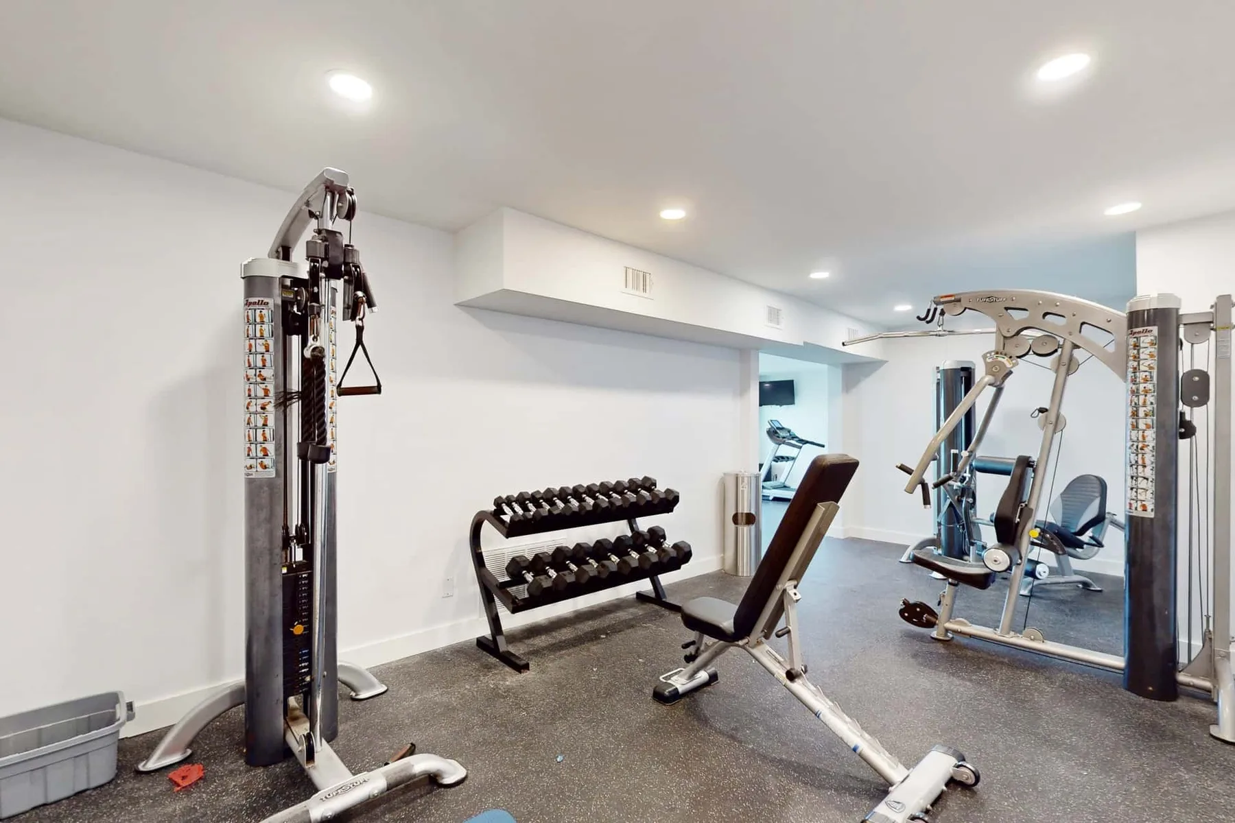 A home gym with weight racks, exercise machines, and a workout bench.