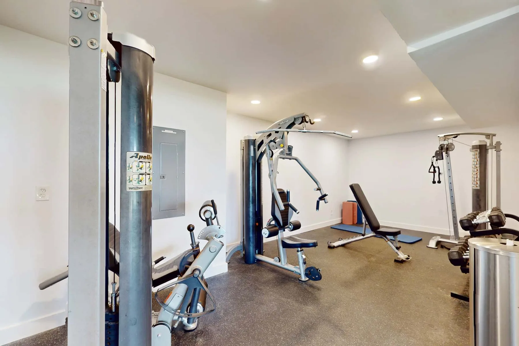 A home gym with exercise machines arranged across a spacious room.