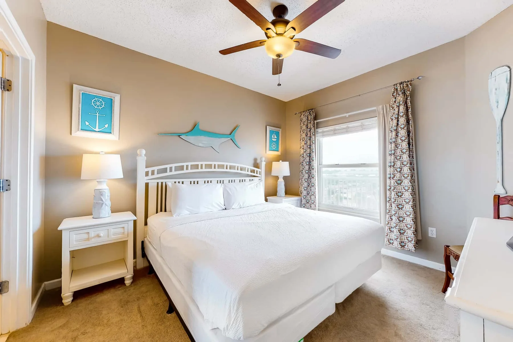 A bright bedroom with a white bed, bedside tables, and a ceiling fan.