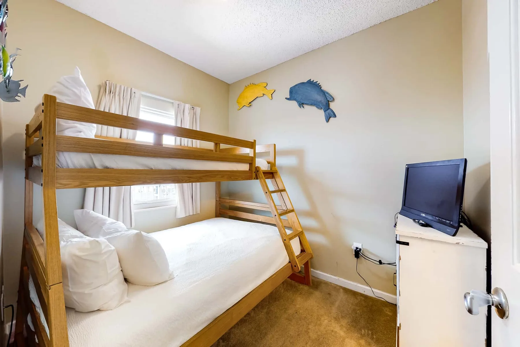 A bedroom with a wooden bunk bed, wall decorations, and a television.