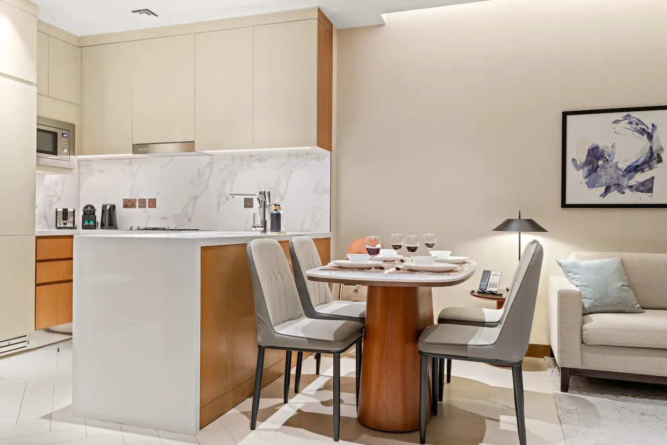 A dining area beside a compact kitchen, with a round table and upholstered seating.