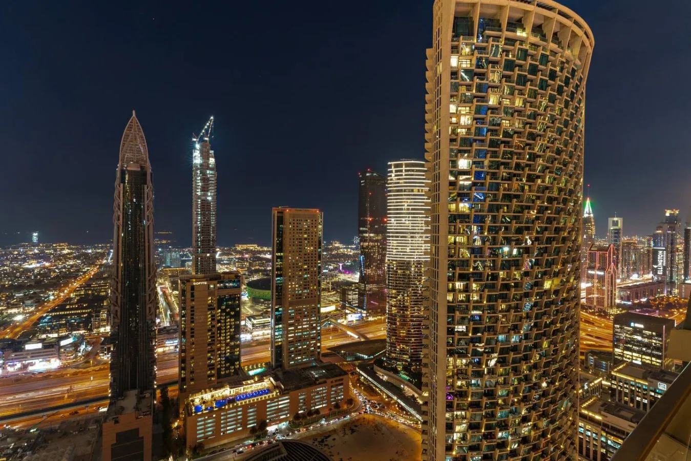 Nighttime city skyline with illuminated high-rise buildings and roads.