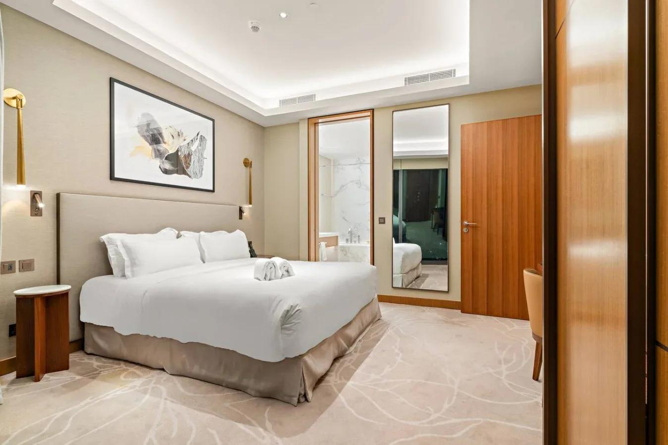 A bright bedroom with a neatly made bed and framed artwork above the headboard.