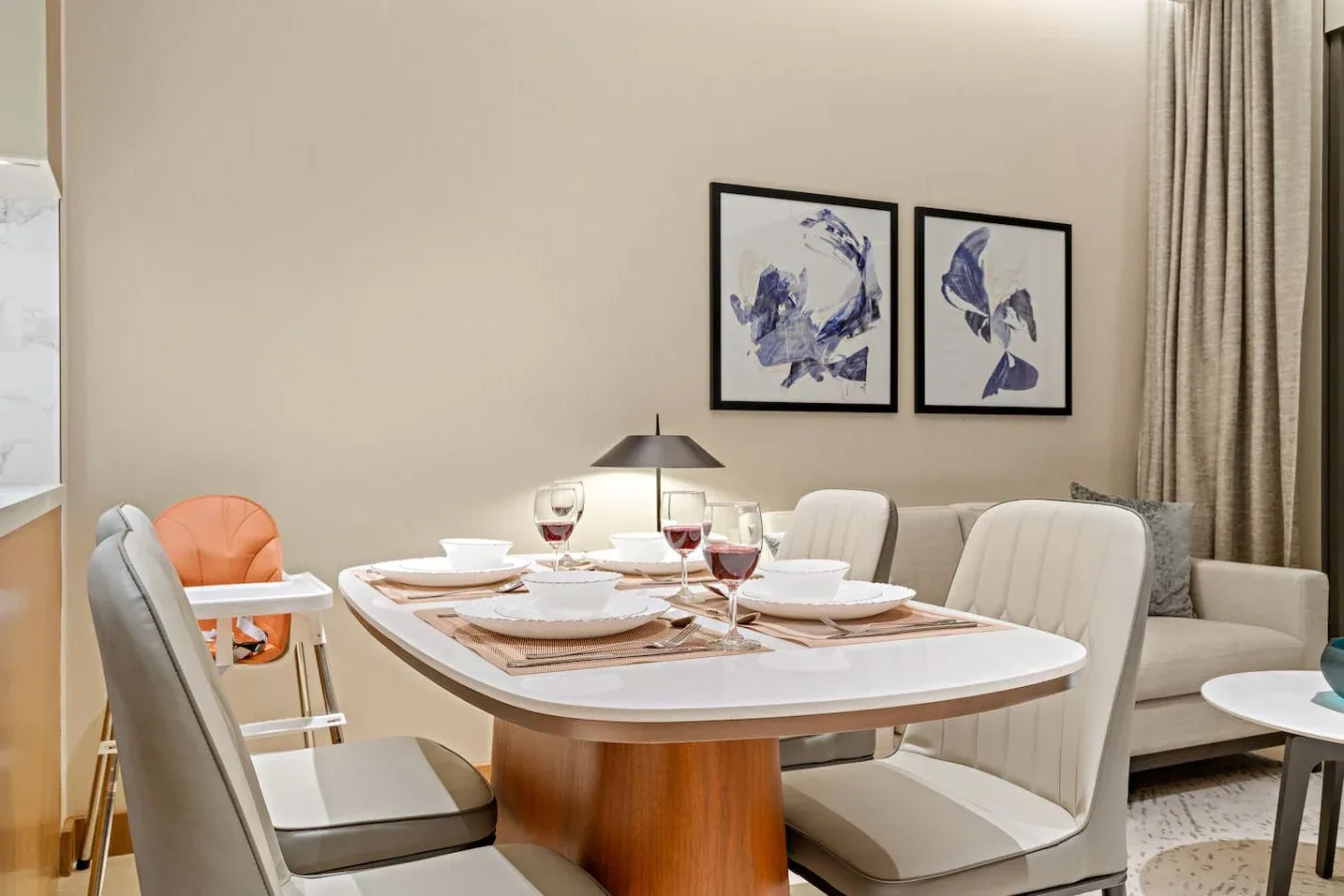 A dining area with a set table and framed artwork on the wall.
