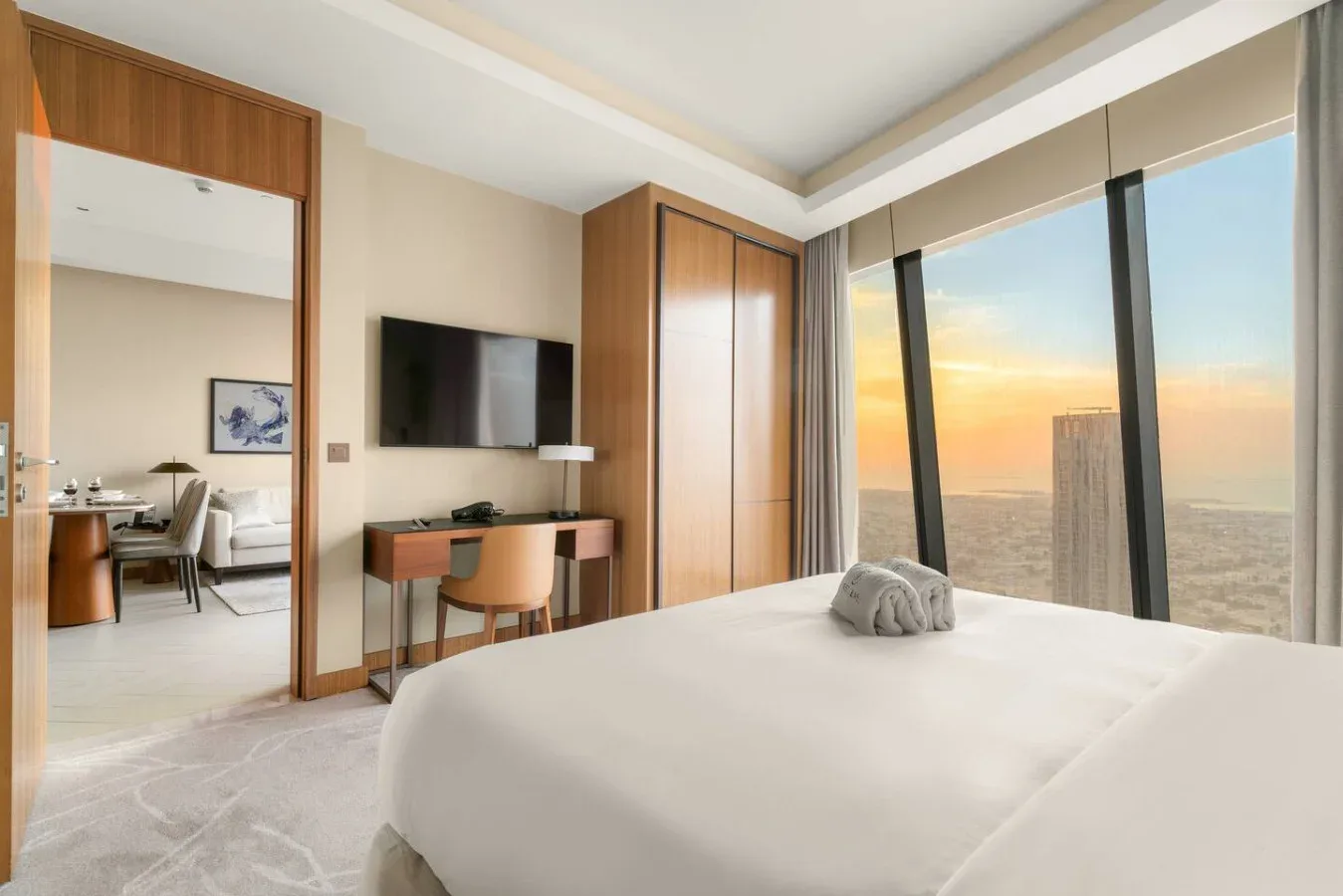 A bedroom with a neatly made bed and large windows overlooking the sea.