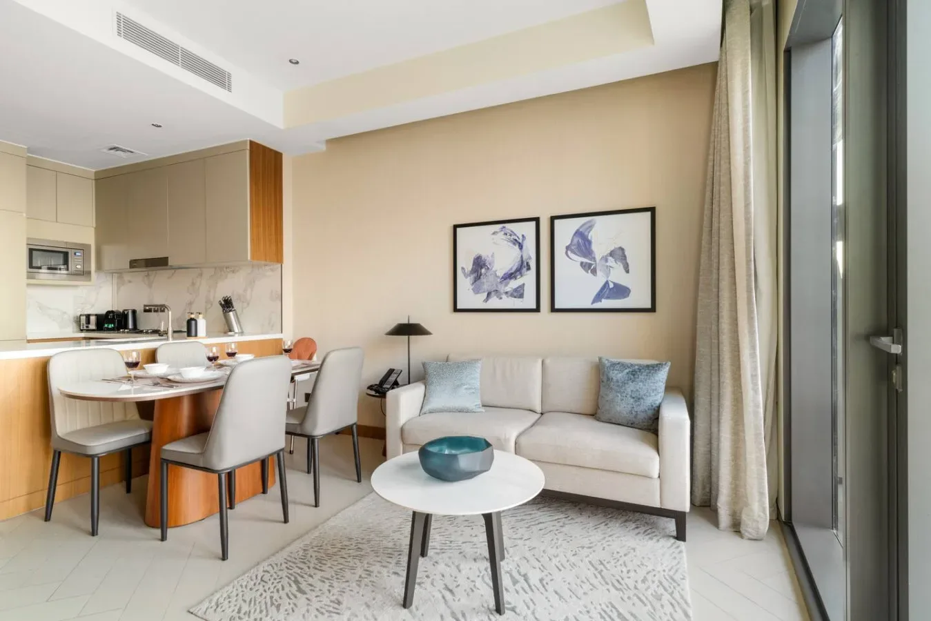 A living area with a sofa and round coffee table beside an open kitchen.