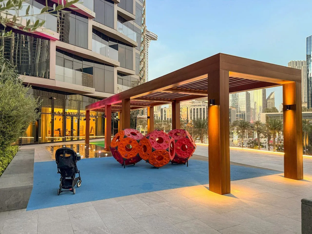An outdoor seating area beneath a wooden pergola, with colorful sculptural chairs.
