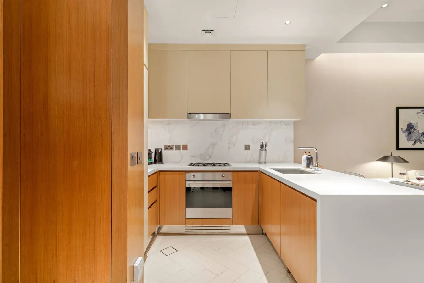 A modern kitchen with wood cabinetry, pale counters, and an island.