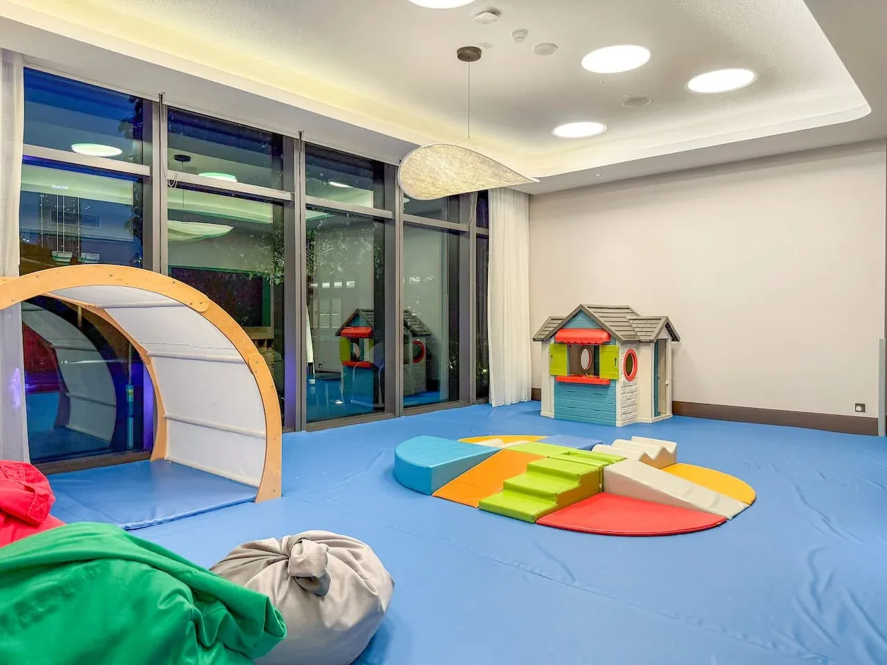 A bright indoor playroom with colorful soft play equipment on a padded floor.