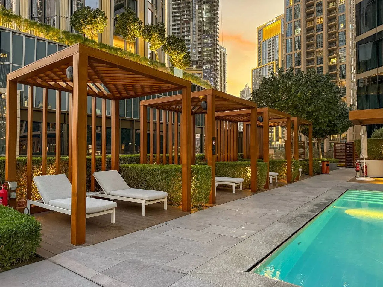 A swimming pool runs alongside a paved terrace with shaded seating.
