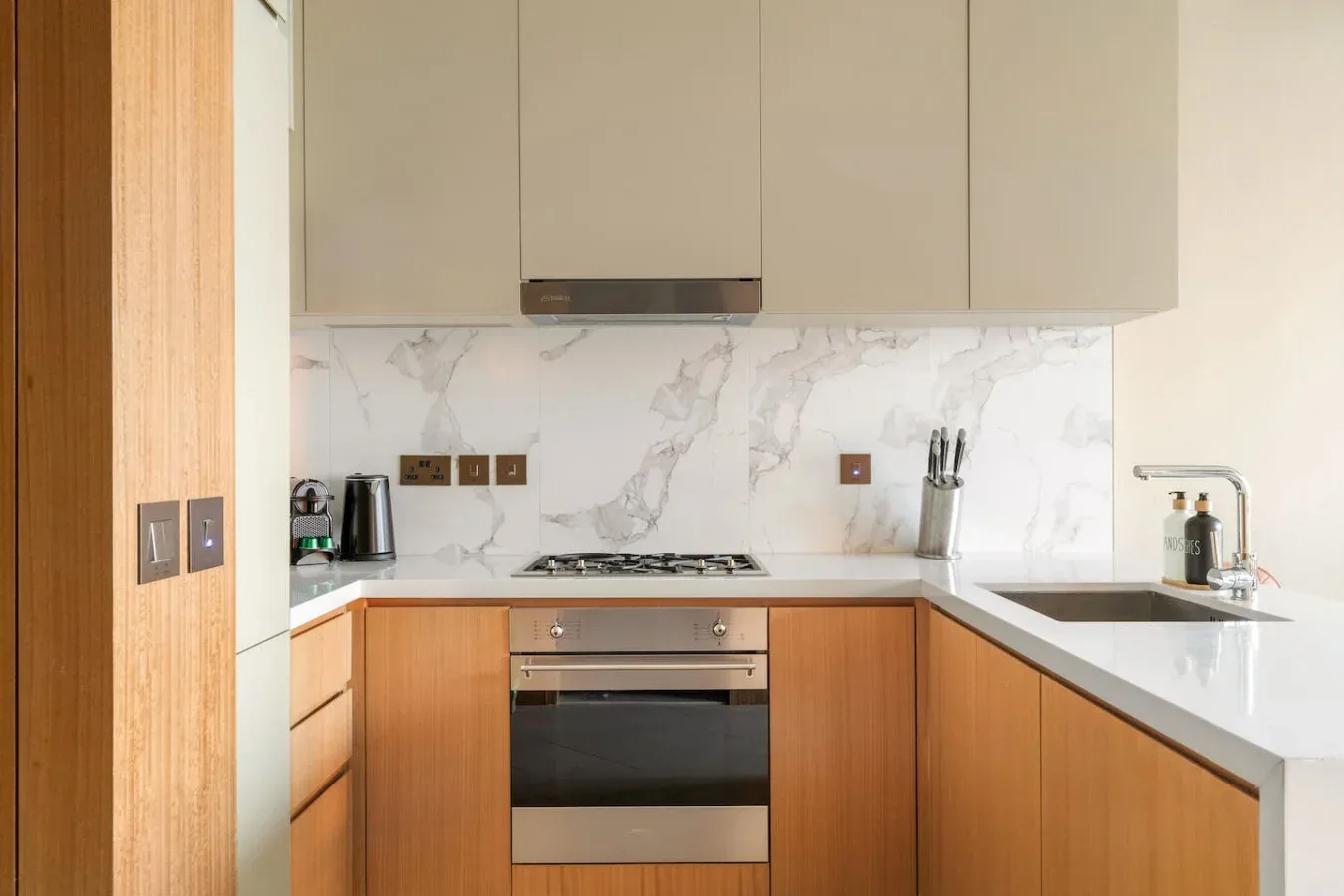 A modern kitchen with wood cabinets, a stovetop, and a sink.