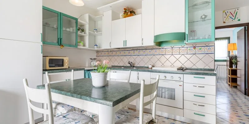 A bright kitchen with white cabinets and a dining table.
