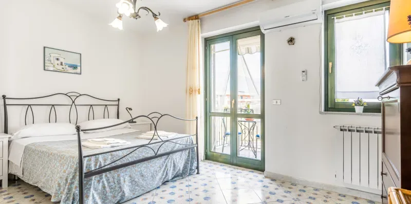 A bedroom with two beds, green-framed glass doors, and a window.
