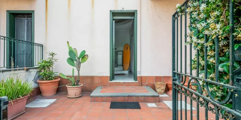 A tiled patio with potted plants and an open doorway.