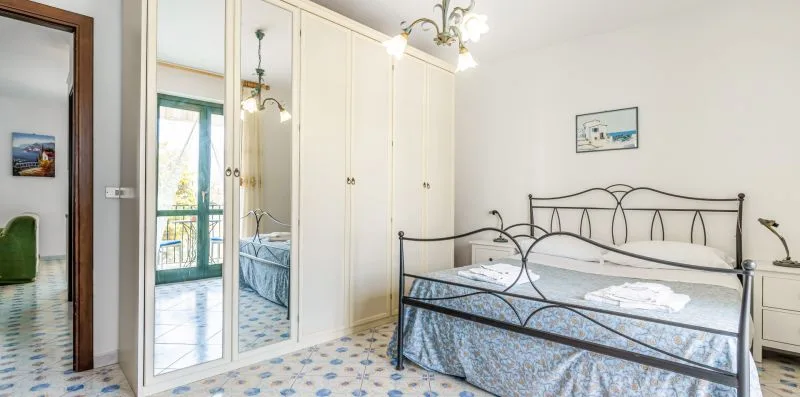 A bedroom with a metal bed beside mirrored wardrobe doors.
