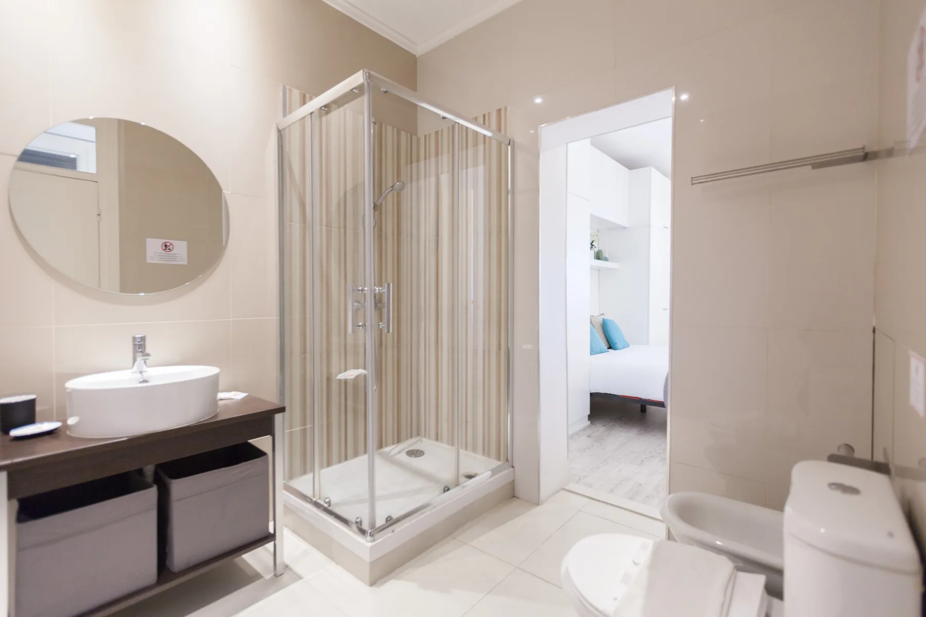 Un baño alicatado con lavabo, ducha e inodoro junto a una puerta abierta.