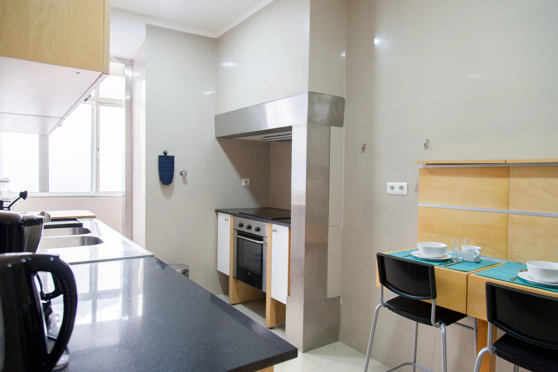 Una cocina luminosa con zona de comedor, encimera, estufa y mesa.