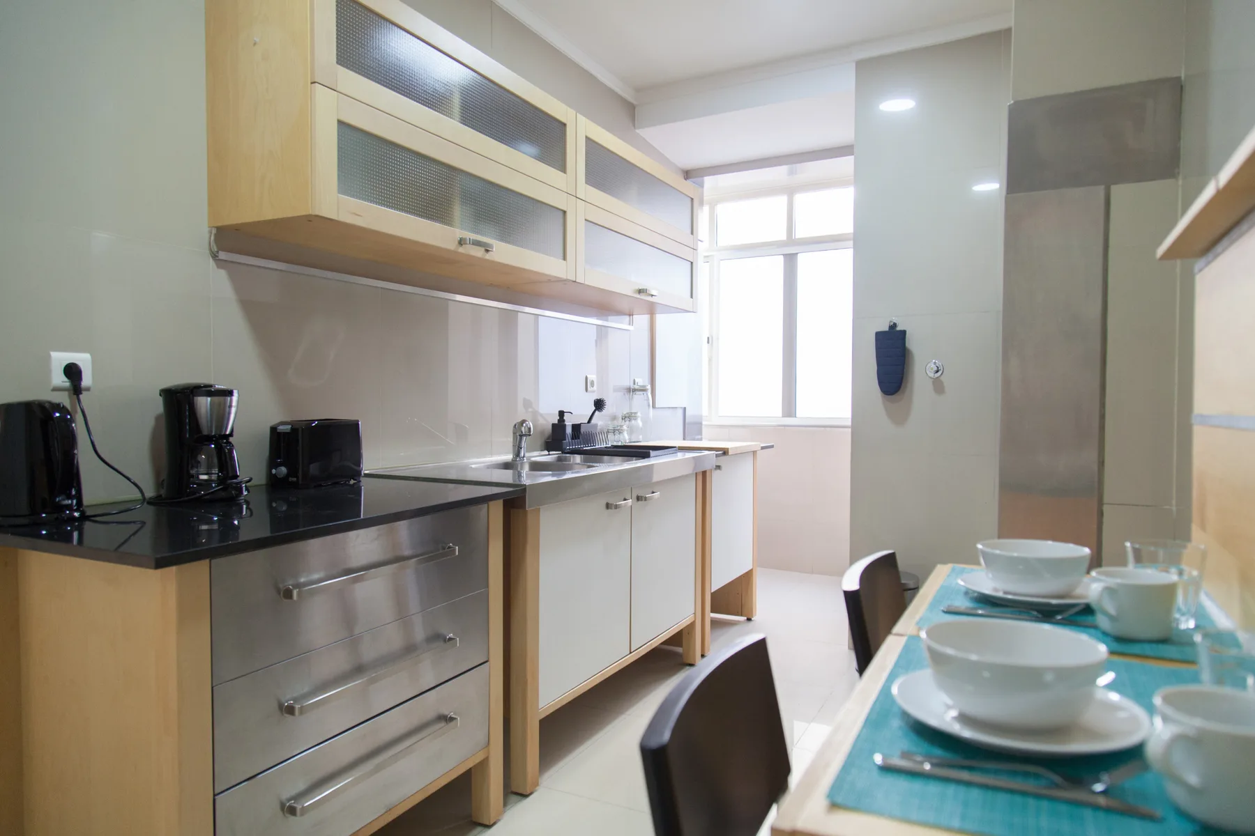 Una cocina moderna con armarios de madera clara y una mesa puesta con platos.
