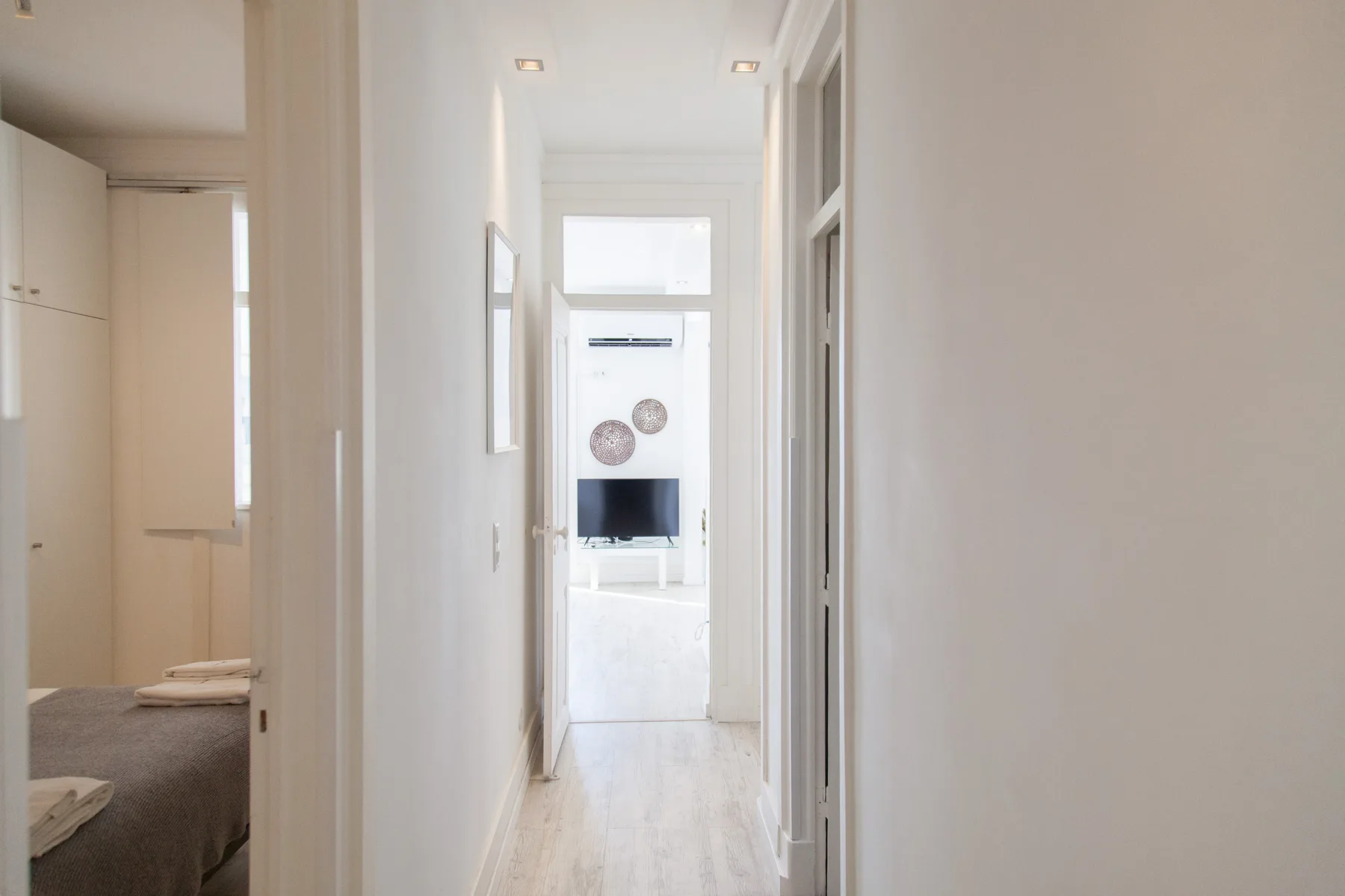 Un pasillo luminoso conduce a una zona de estar con un televisor.