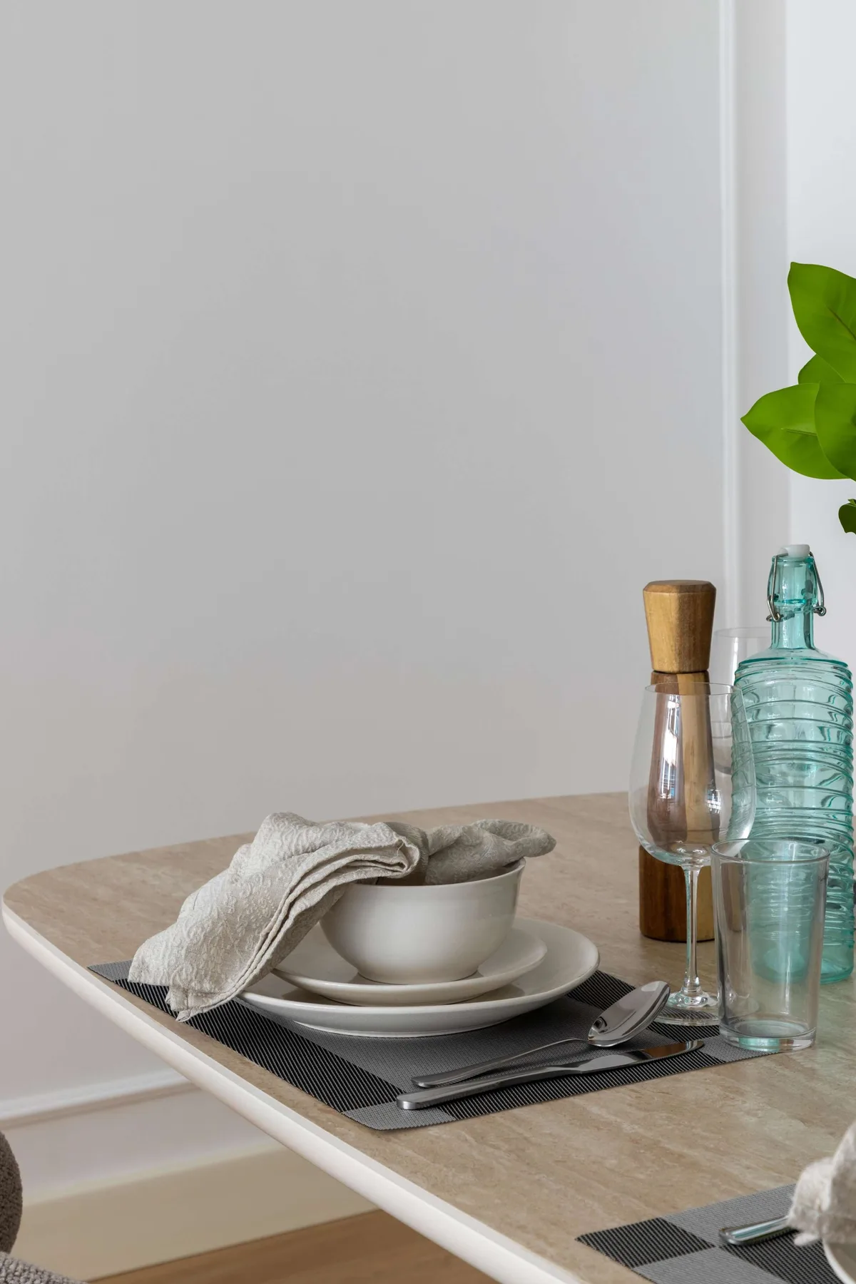 A dining table is set with plates, cutlery, and glass bottles.