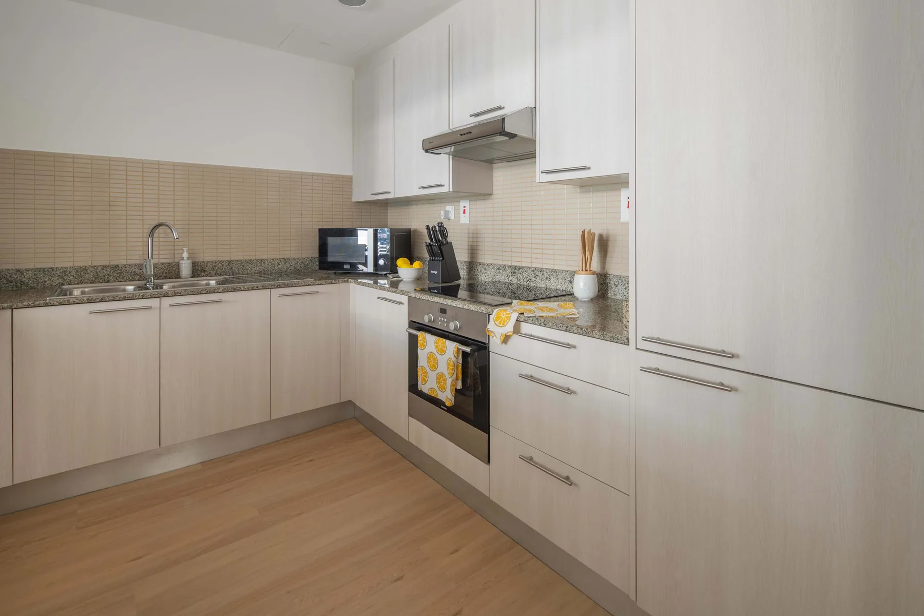 A bright kitchen with pale cabinets, a countertop, and a built-in oven.