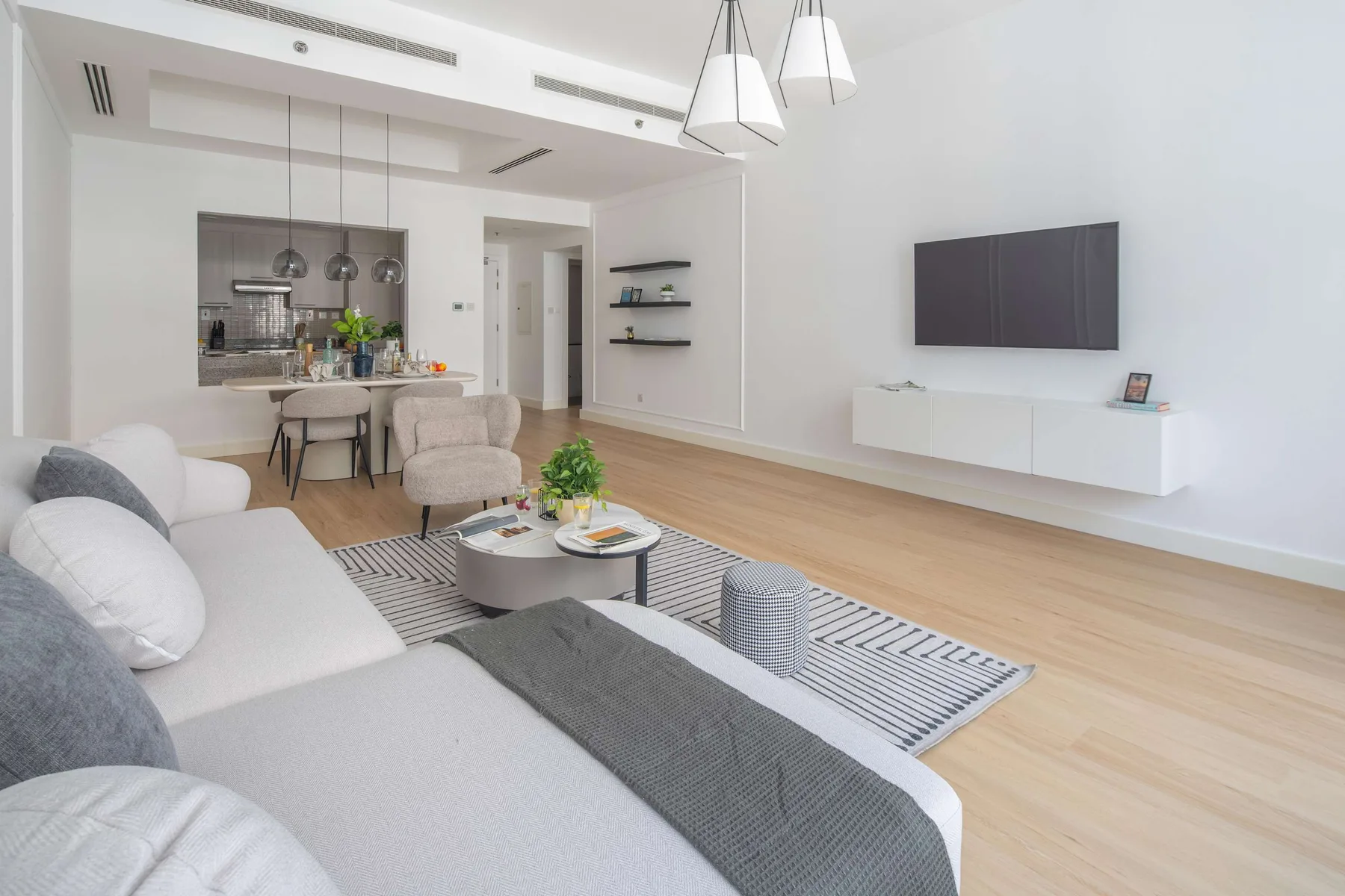 Una luminosa sala de estar de concepto abierto, con zona de descanso y cocina al fondo.