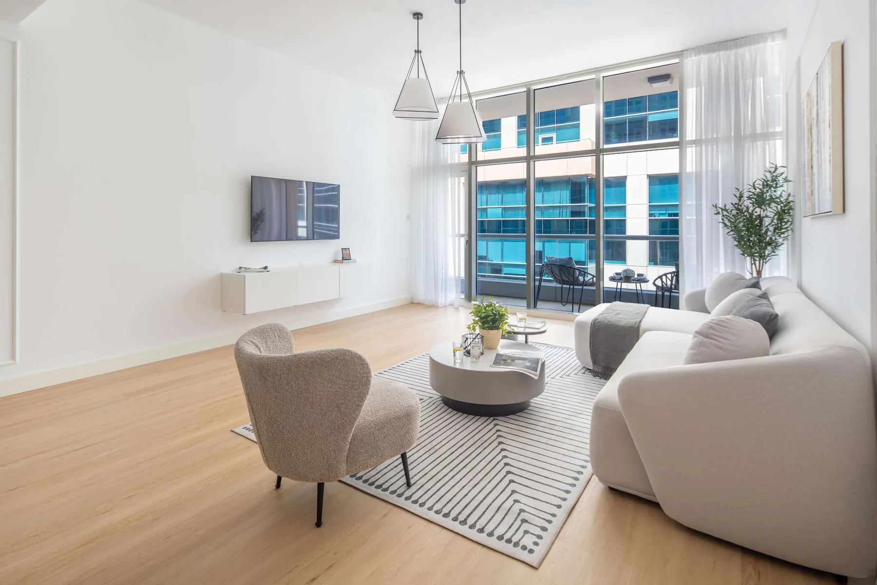 Sala de estar luminosa con asientos alrededor de una mesa de centro junto a ventanales.