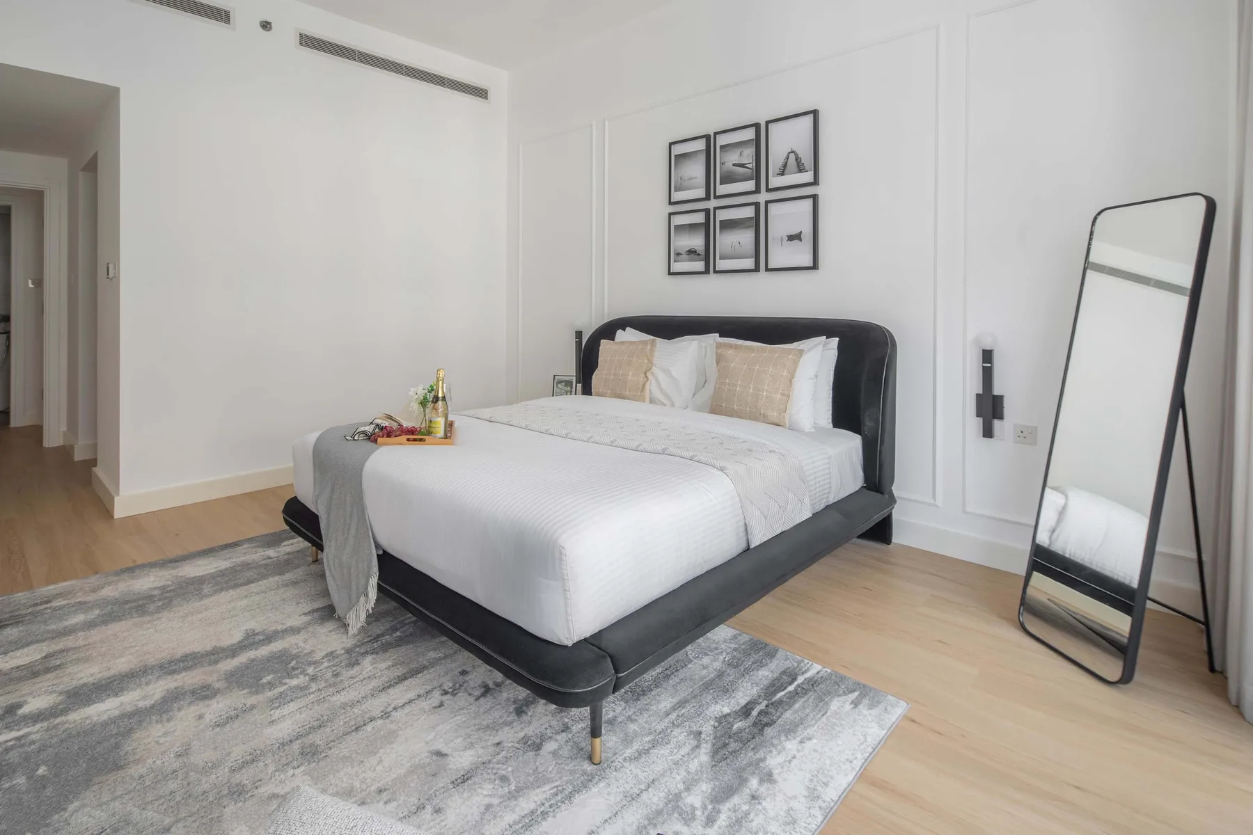 A bright bedroom with a neatly made bed and framed pictures above it.