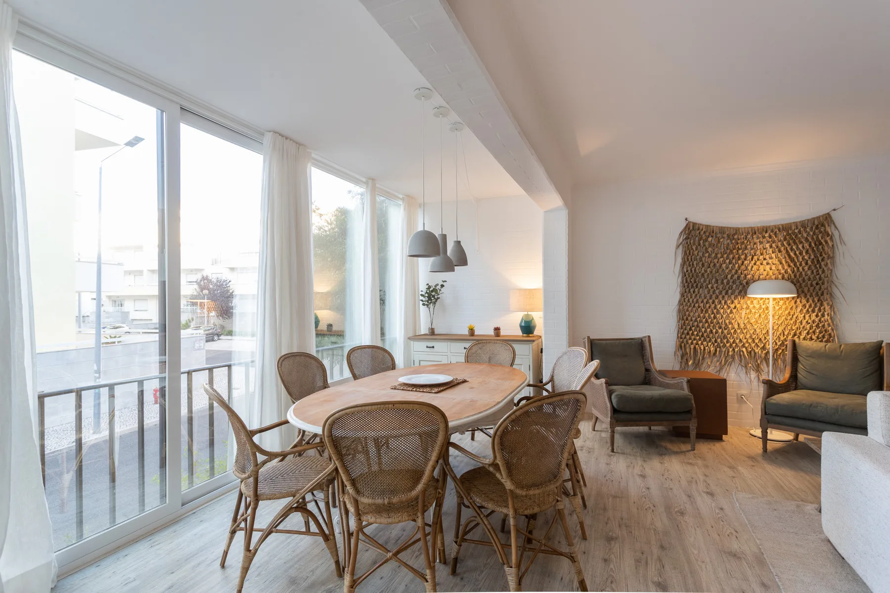 A bright open-plan living and dining area with large windows and a table.