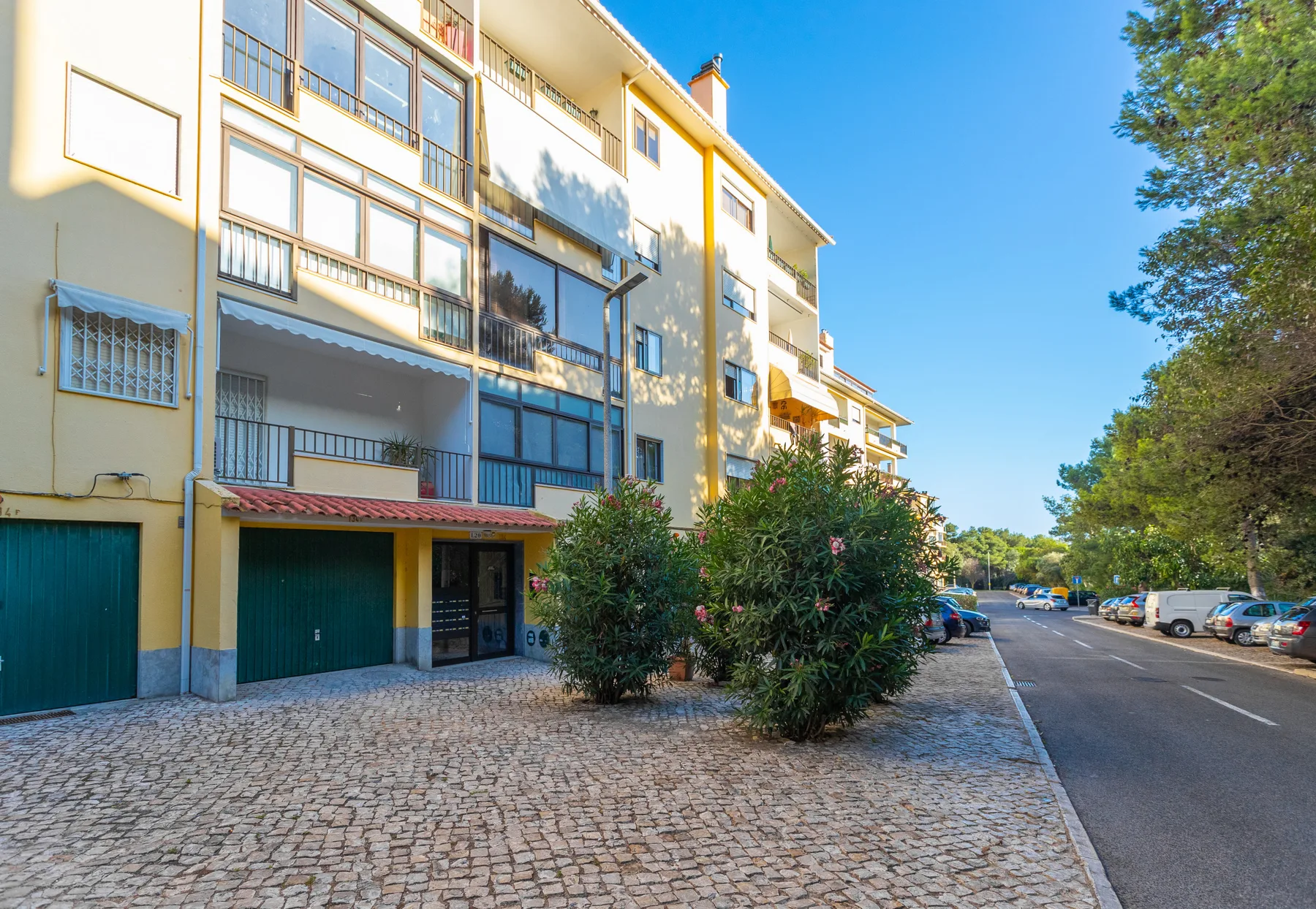 A residential apartment building stands beside a paved sidewalk and street.
