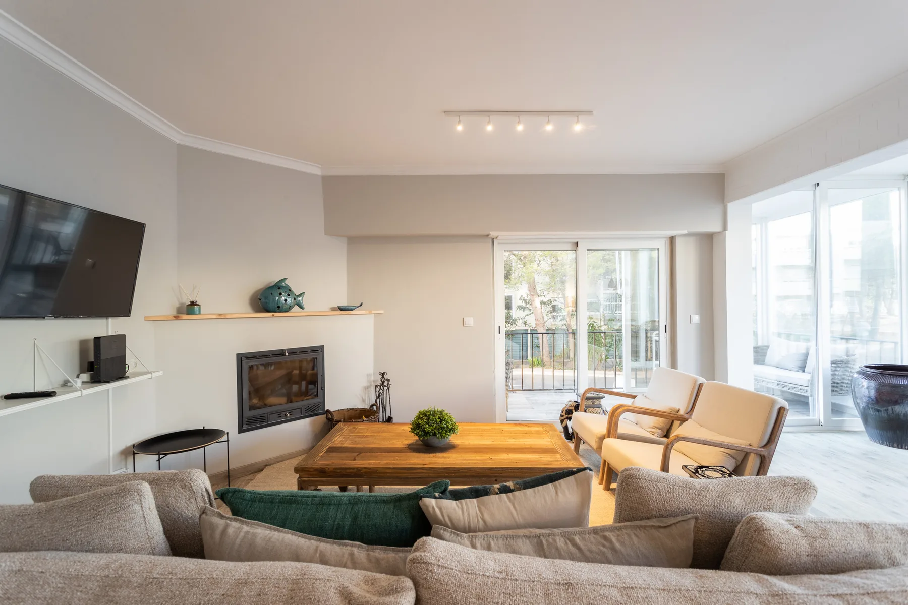 A bright living room with seating, a fireplace, and large glass doors.