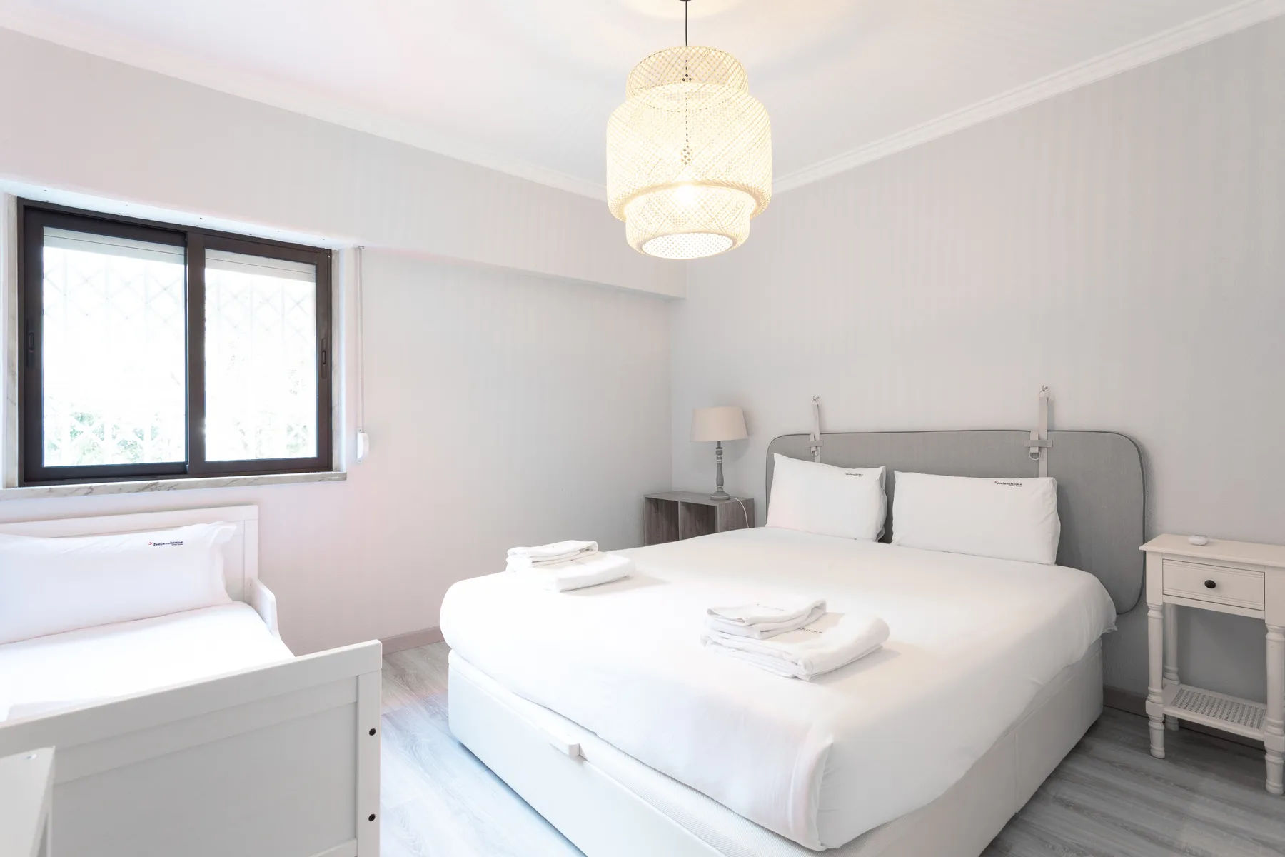 Un dormitorio luminoso con una cama grande, una cama individual y una ventana.