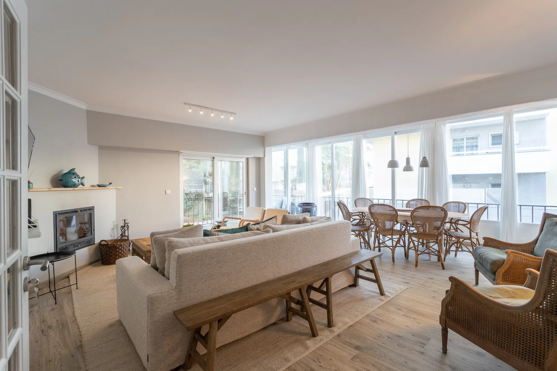 A bright living and dining area with seating beside large windows.