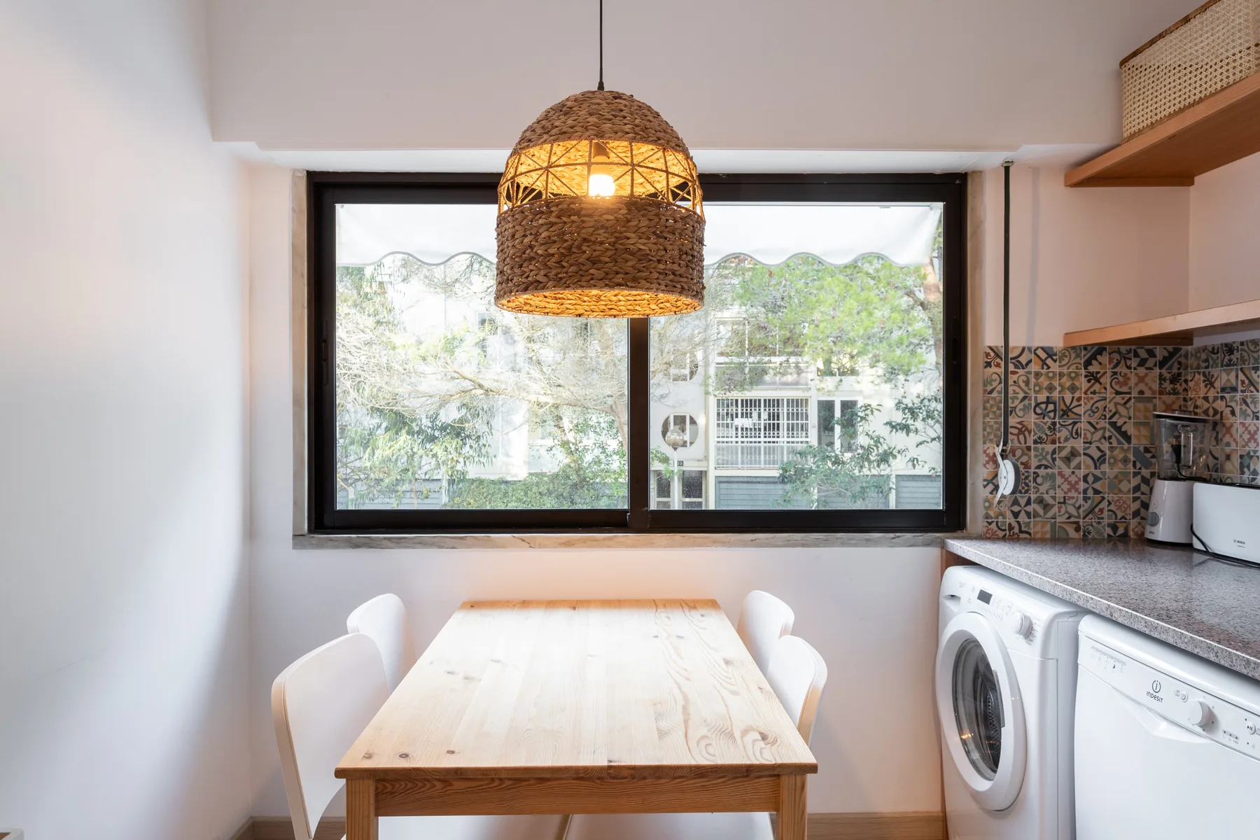 A dining area with a wooden table beside a compact kitchen.